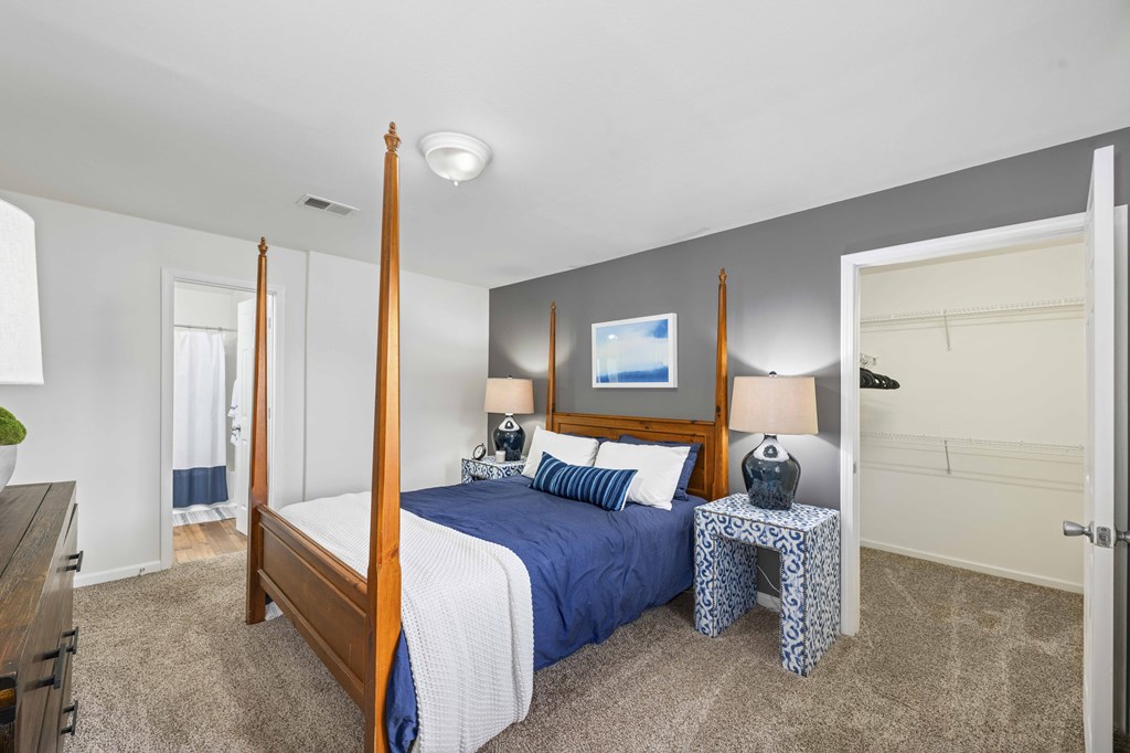 A bedroom with a four poster bed and a blue bedspread.