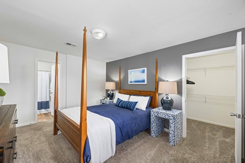 A bedroom with a four poster bed and a blue bedspread.