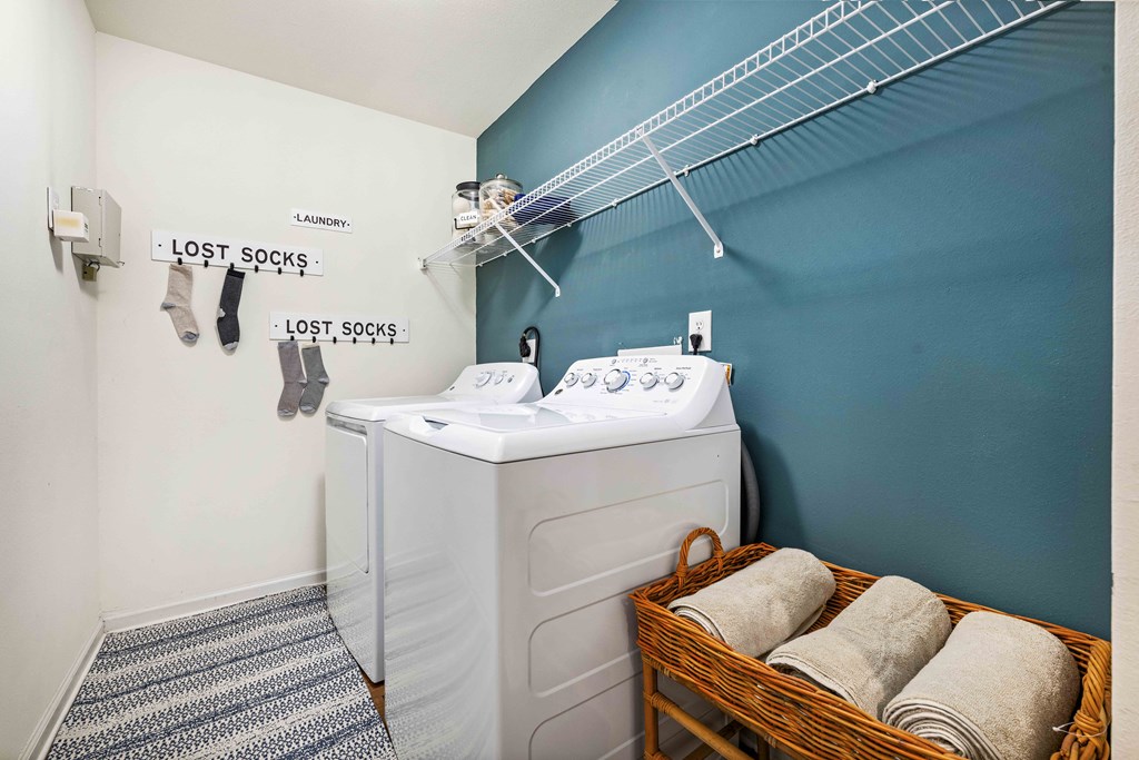 A laundry room with a washer and dryer and a basket of towels.