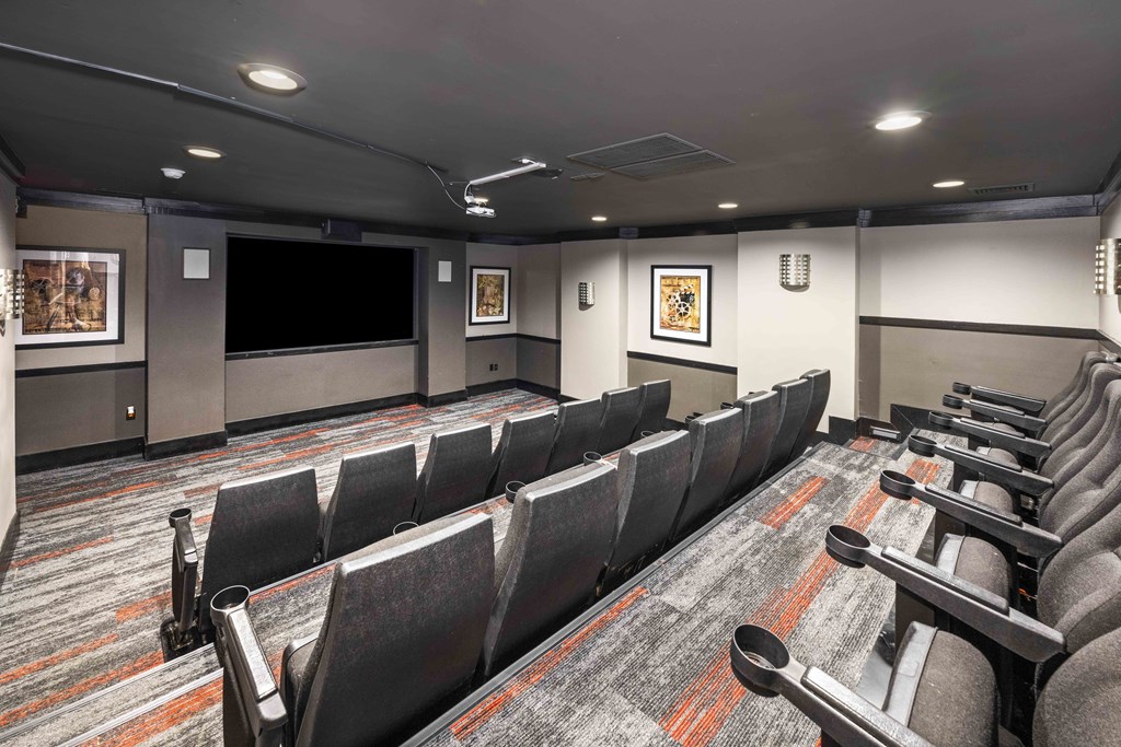 A row of grey chairs are arranged in a room with a carpeted floor.
