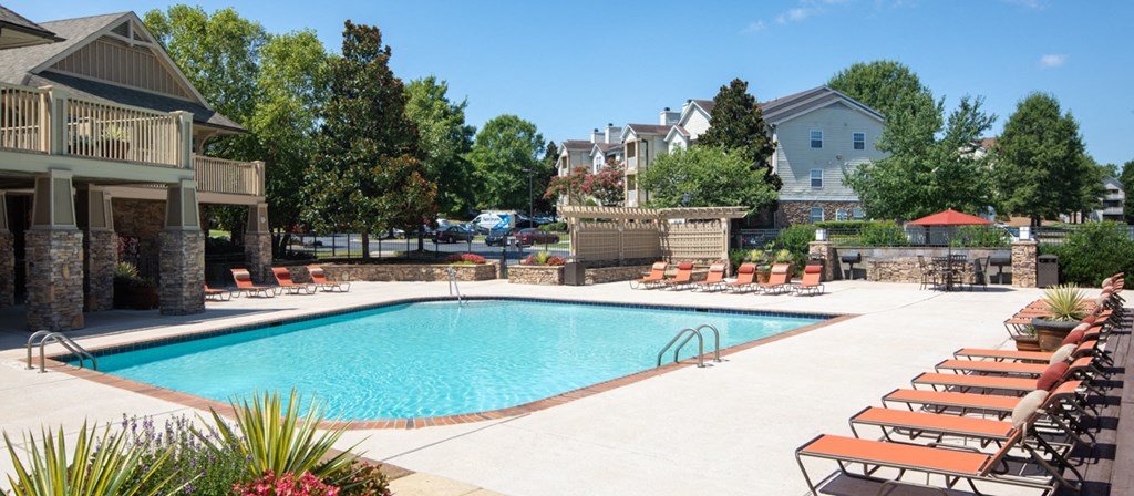 a swimming pool with lounge chairs around it in front of a house