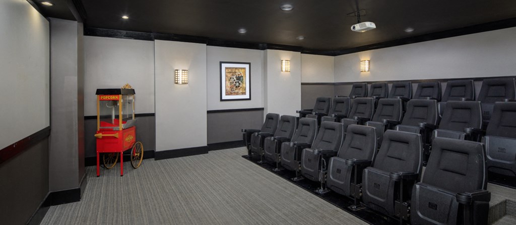 an empty theater room with rows of black chairs and a red podium in the center
