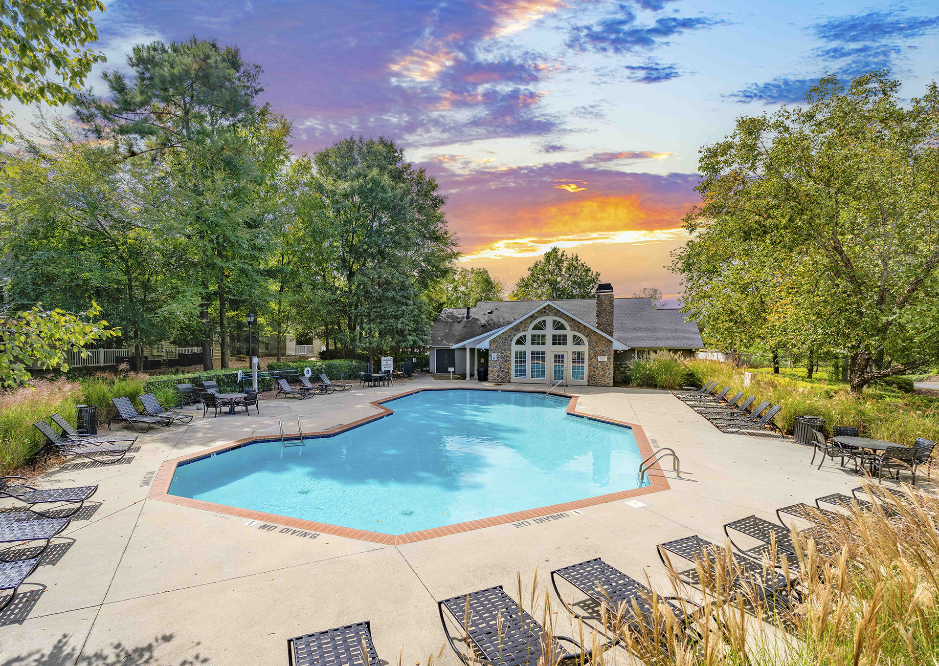 a swimming pool with chairs around it and a house in the background
