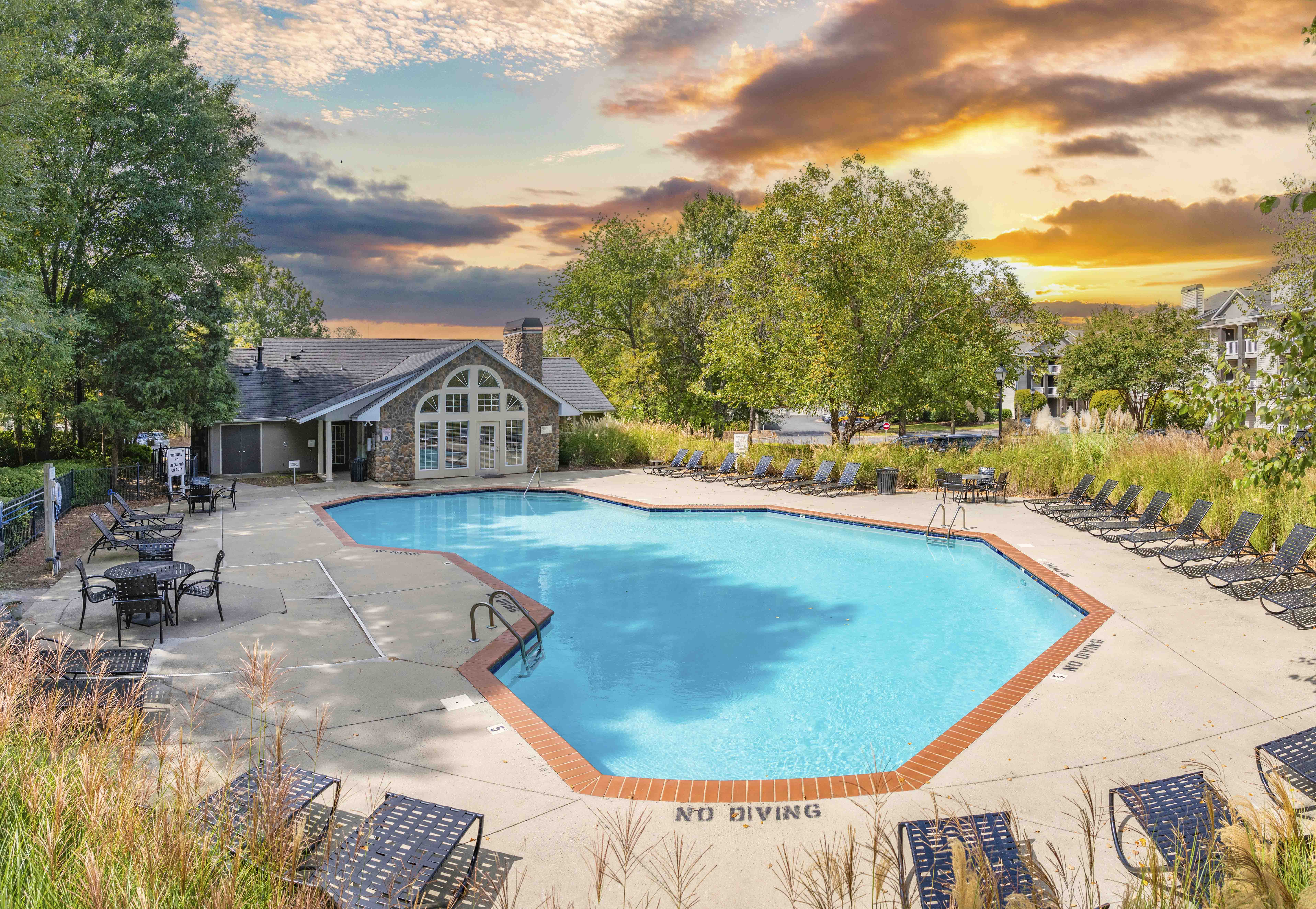 a swimming pool with chairs around it and a house in the background