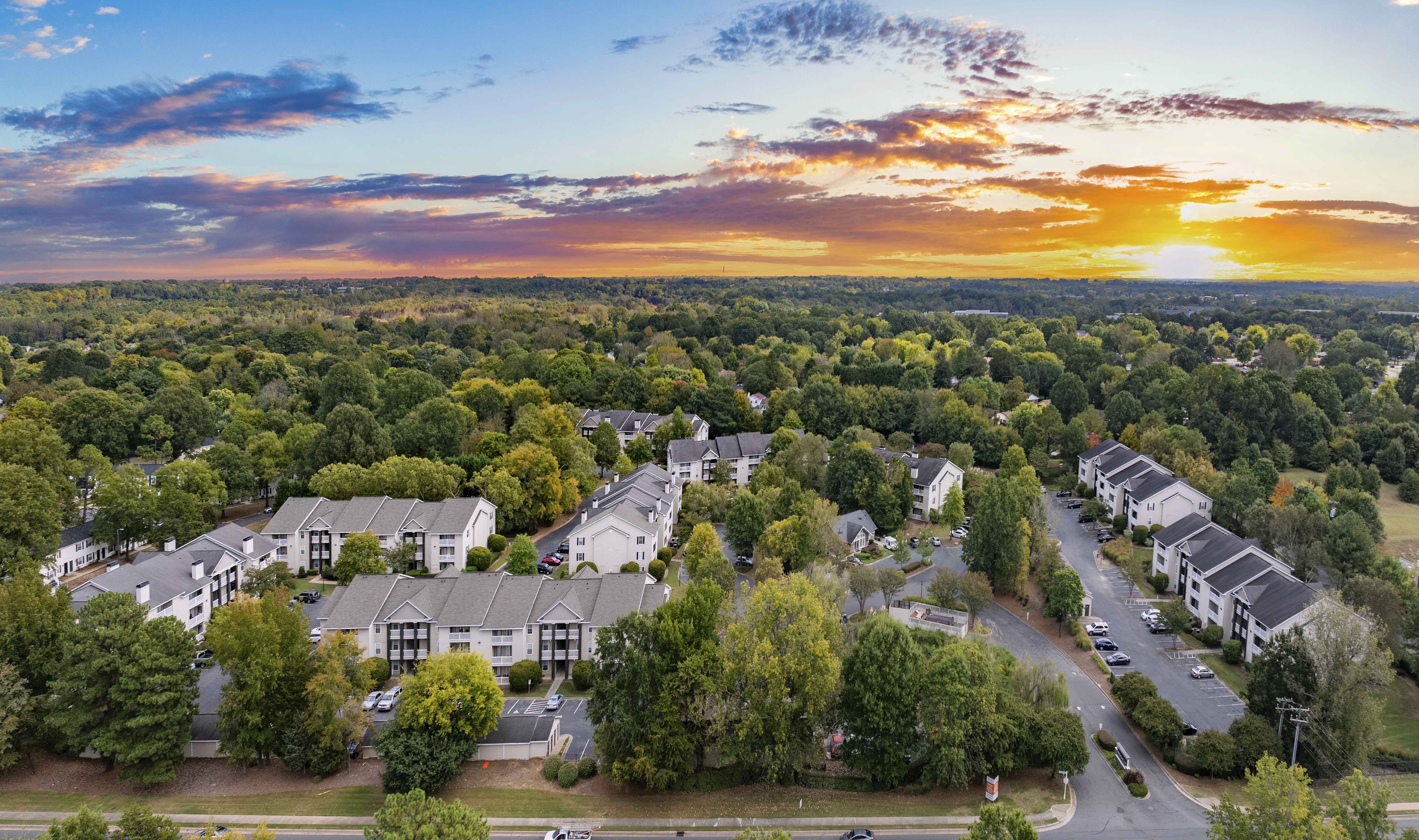 an aerial view of a neighborhood of houses and trees at sunset