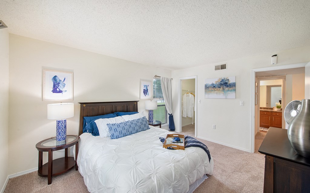 a bedroom with a bed and a dresser and a bathroom