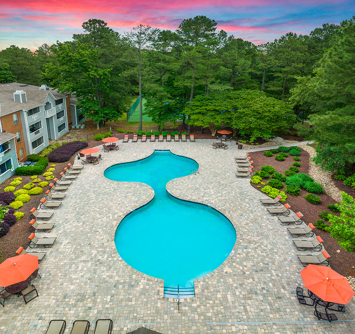 an aerial view of a swimming pool and patio with umbrellas