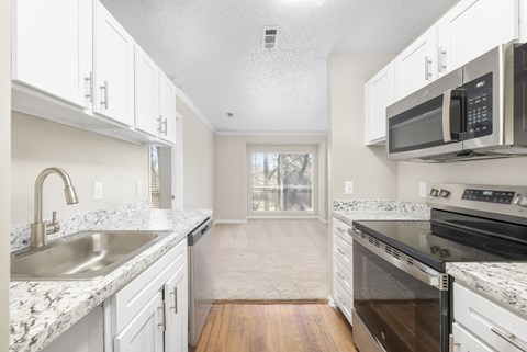 A kitchen with white cabinets and granite countertops.