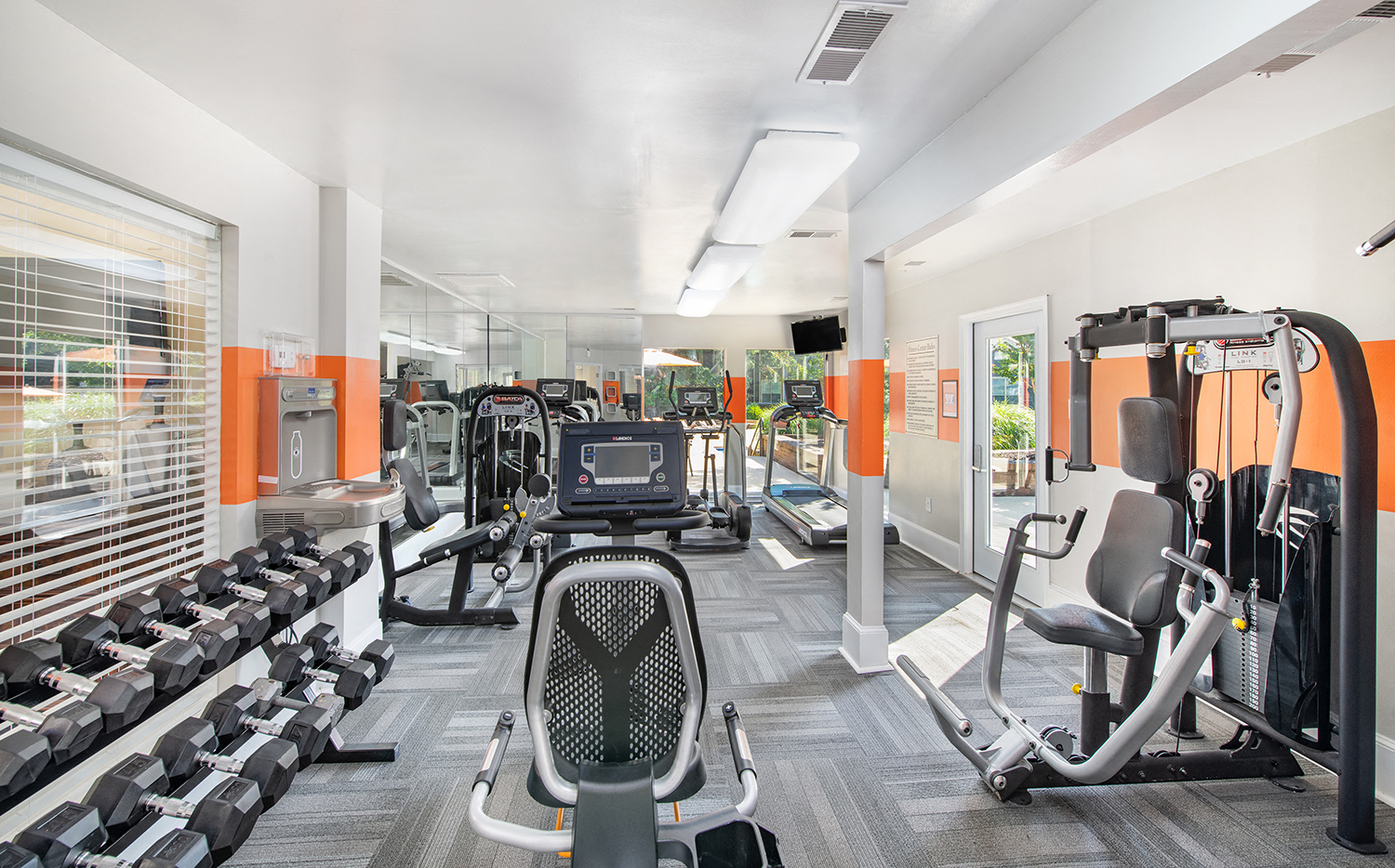 a gym with cardio equipment and weights on the floor