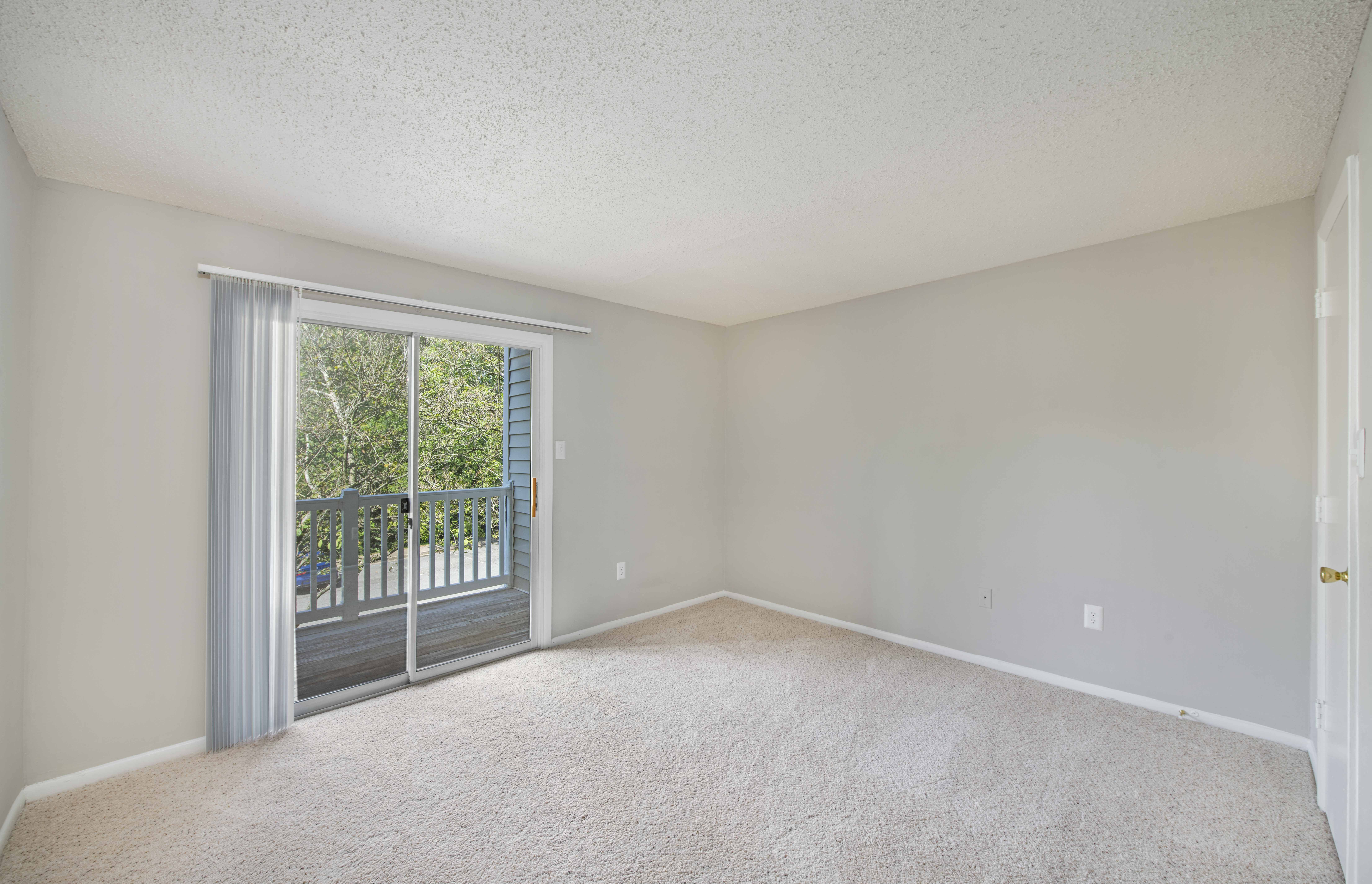 an empty living room with sliding glass doors to a balcony
