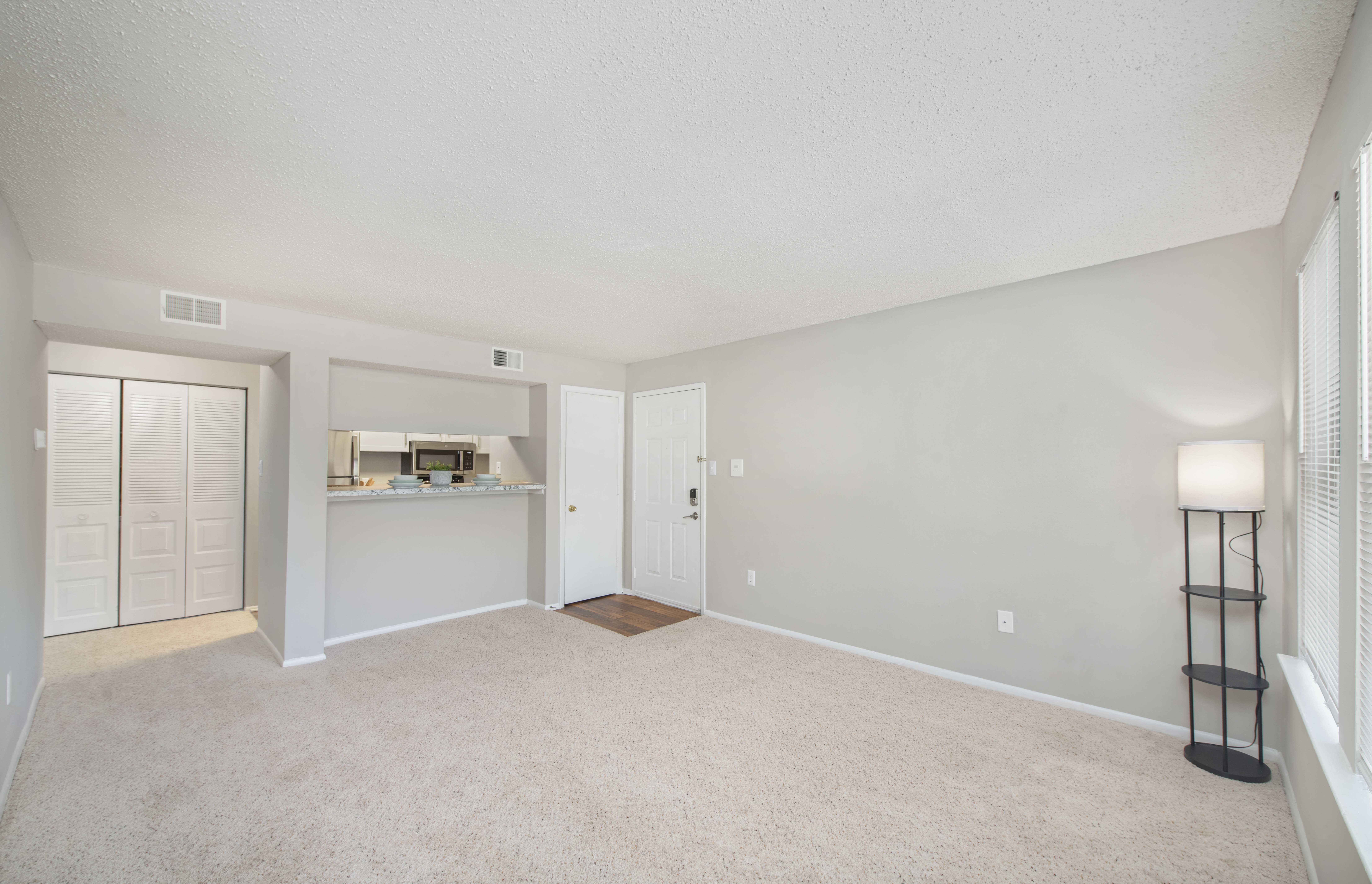 an empty living room and kitchen with white walls and carpeting