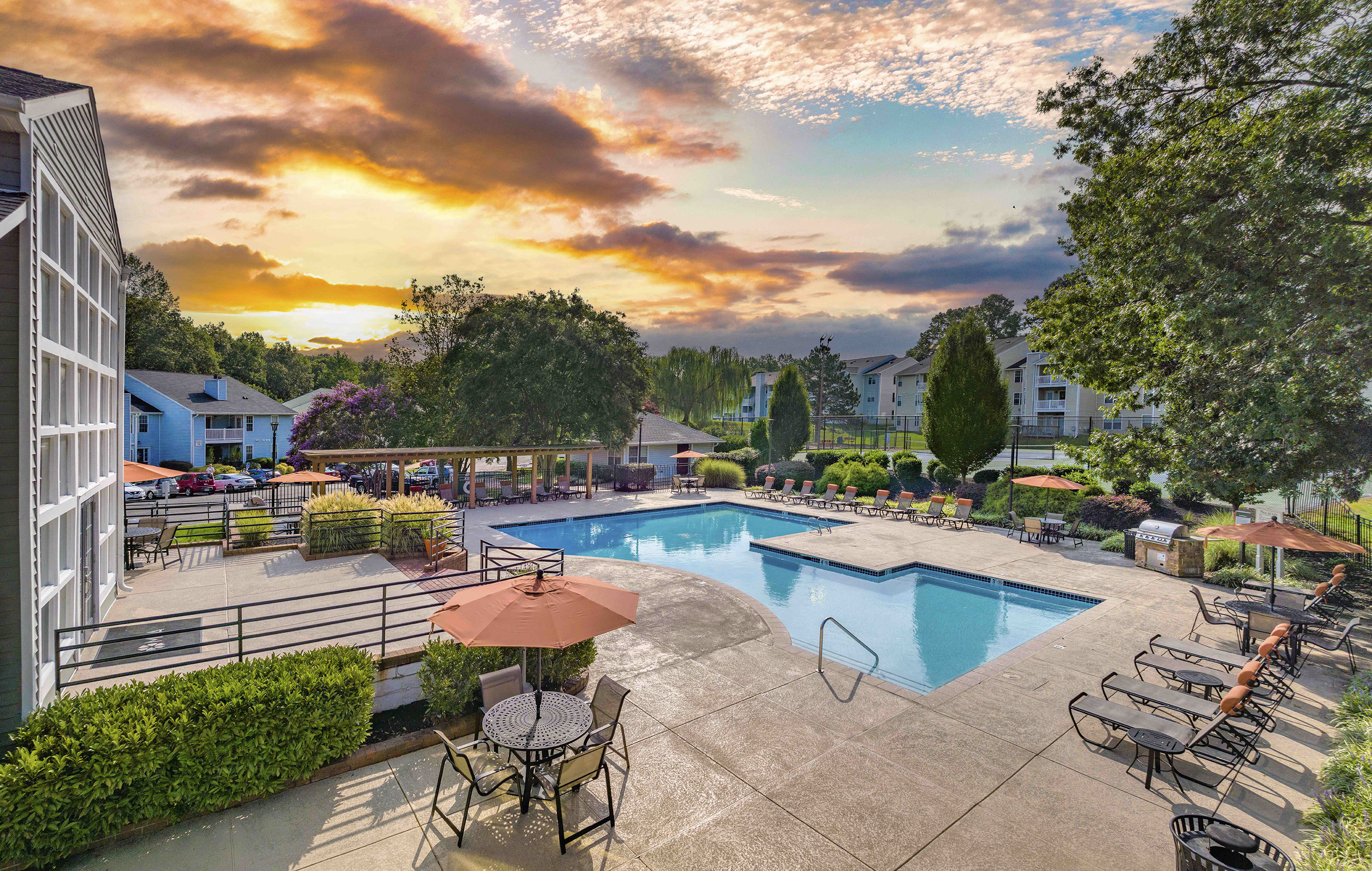 a swimming pool with chairs and umbrellas at sunset