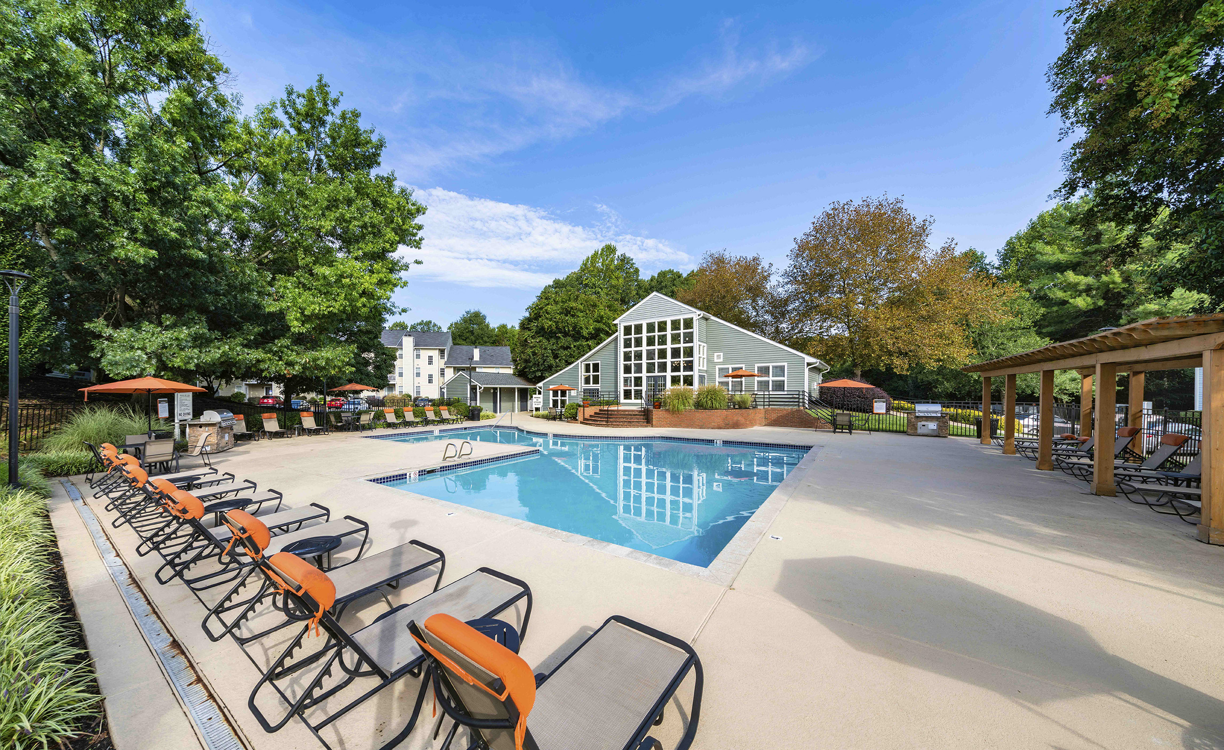 a swimming pool with chairs around it and a house in the background