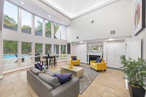 A living room with a grey couch, yellow chairs, and a fireplace.