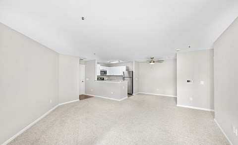 A spacious empty room with a fan and a window.