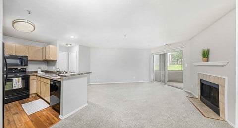 A kitchen with a black oven and microwave, wooden cabinets, and a grey countertop.