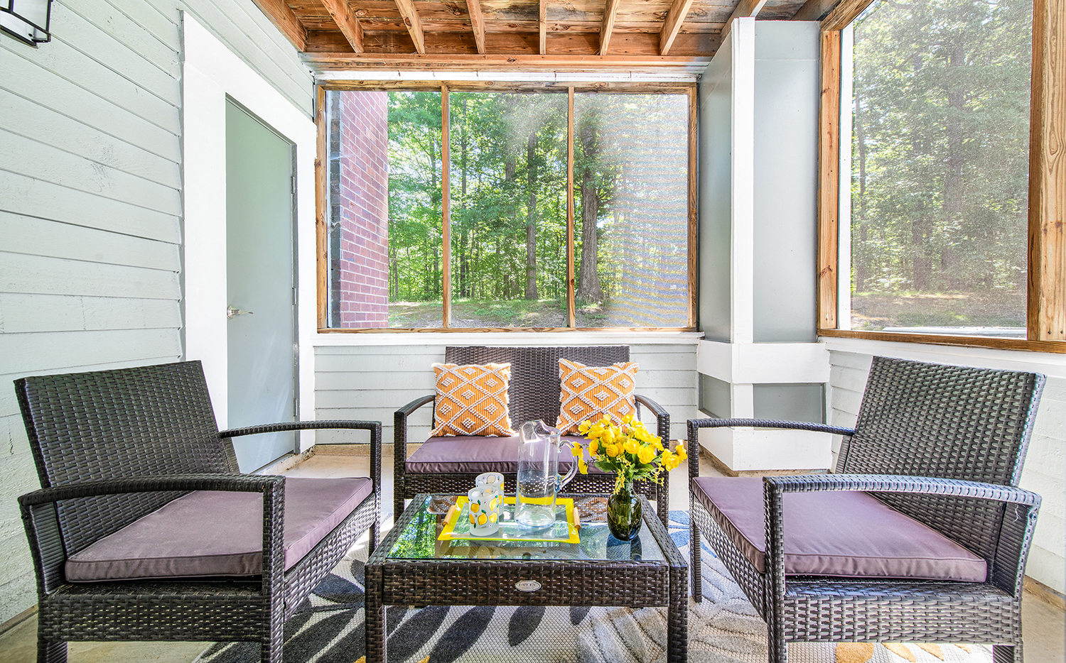a screened porch with chairs and a table with flowers