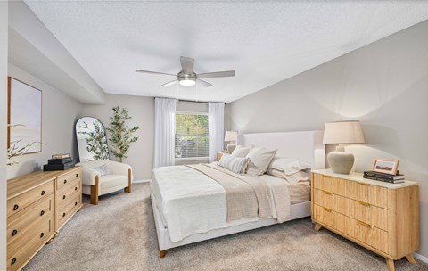 A bedroom with a large bed, a dresser, and a ceiling fan.