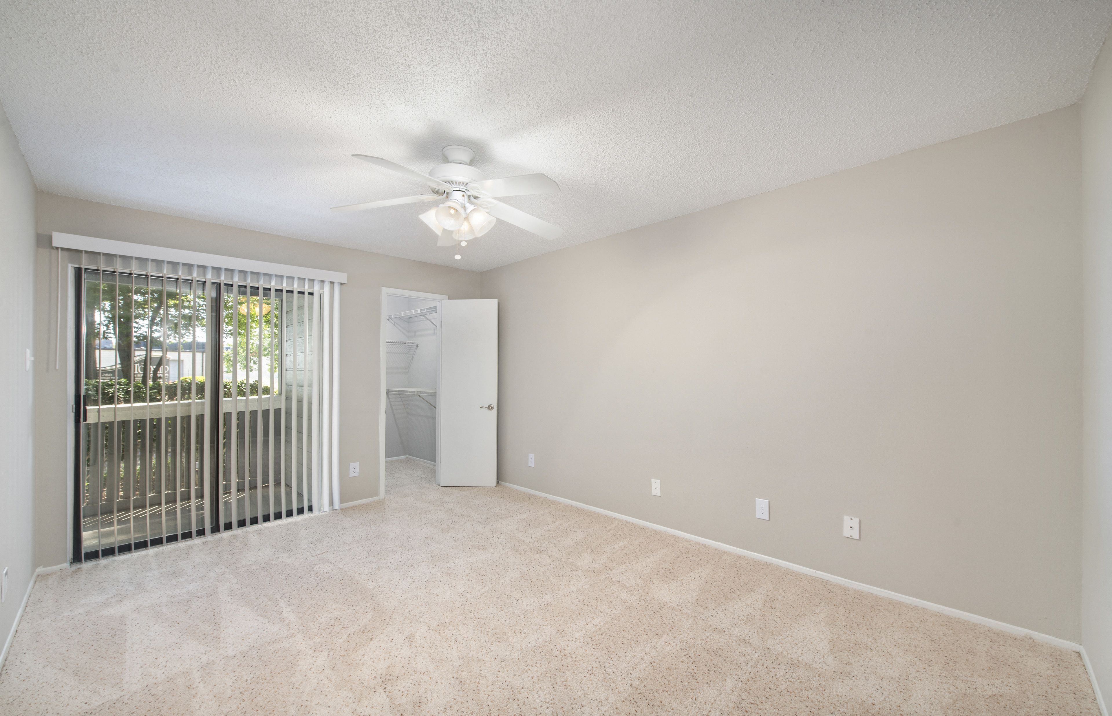 an empty living room with a ceiling fan and a window