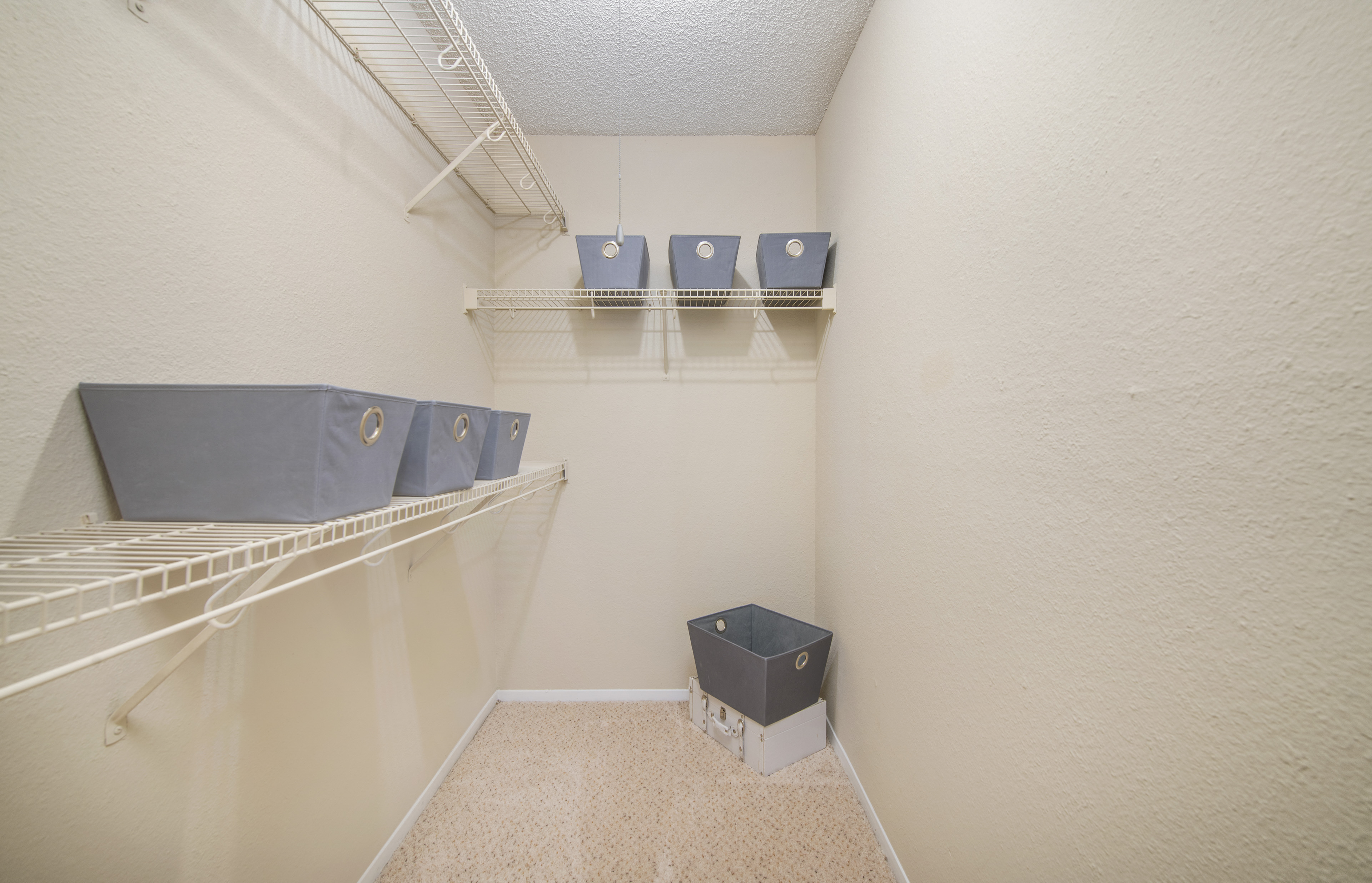a spacious closet with shelves and a trash can in the corner of a room