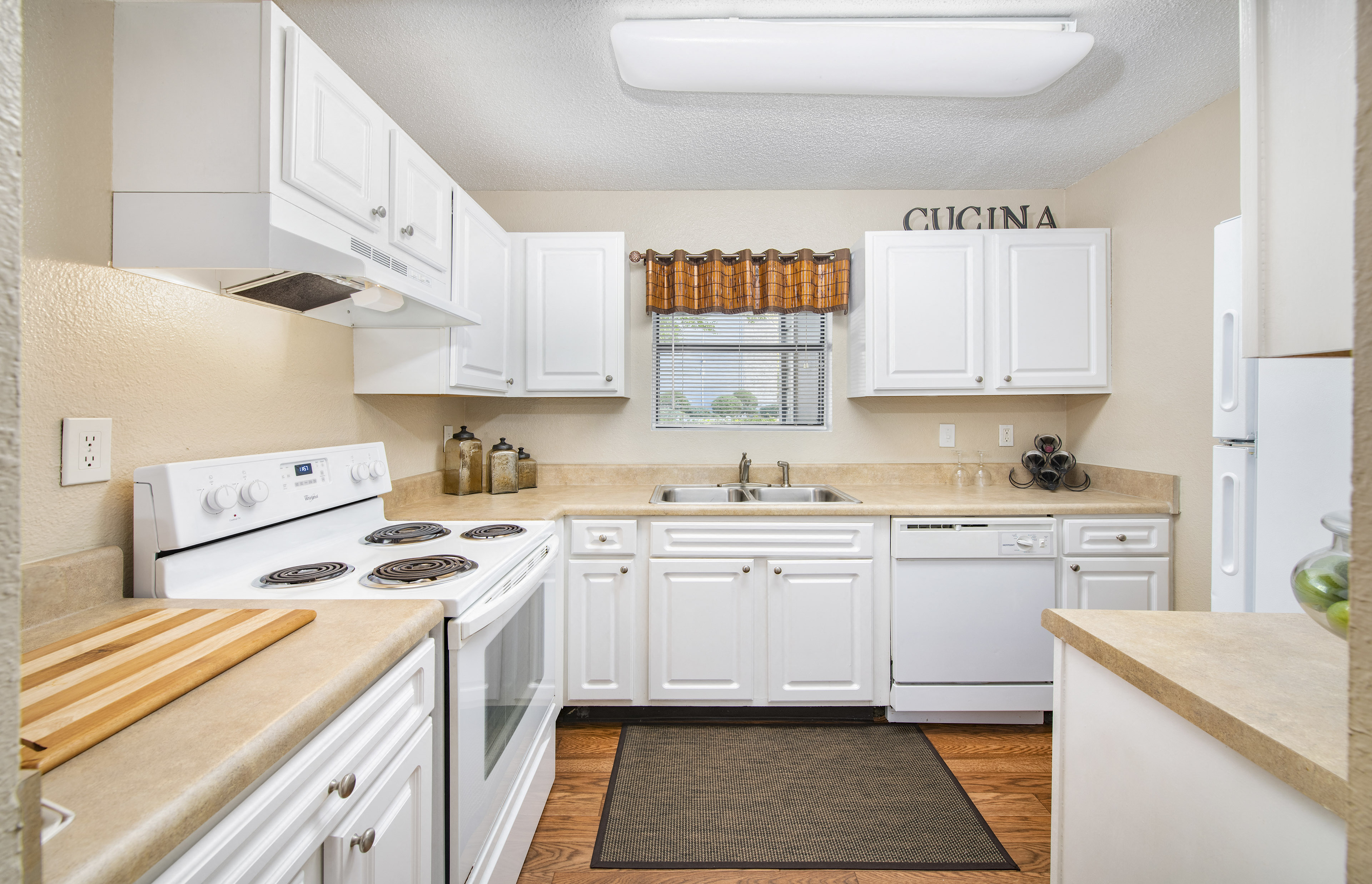 a kitchen with white cabinets and appliances and a counter top and a sink