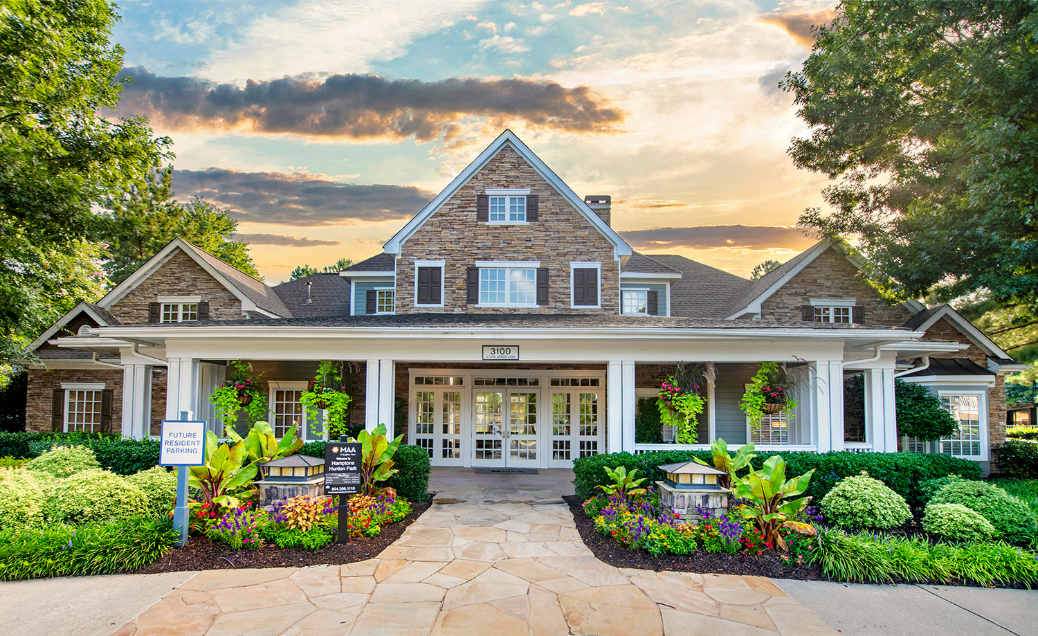 the front of a house with flowers and a sign in front of it