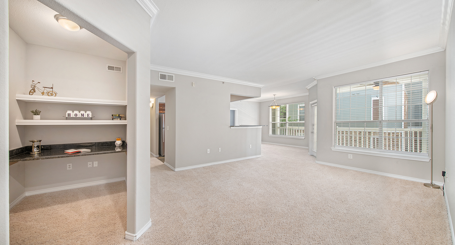 a spacious living room with a kitchen and a large window
