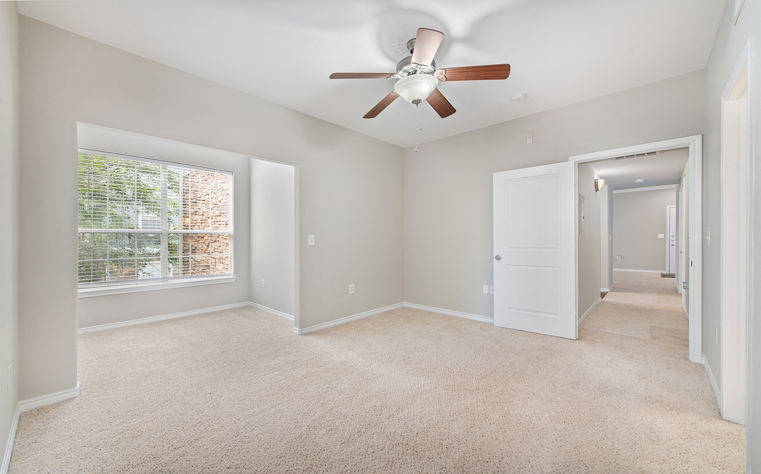 an empty living room with a ceiling fan and a window