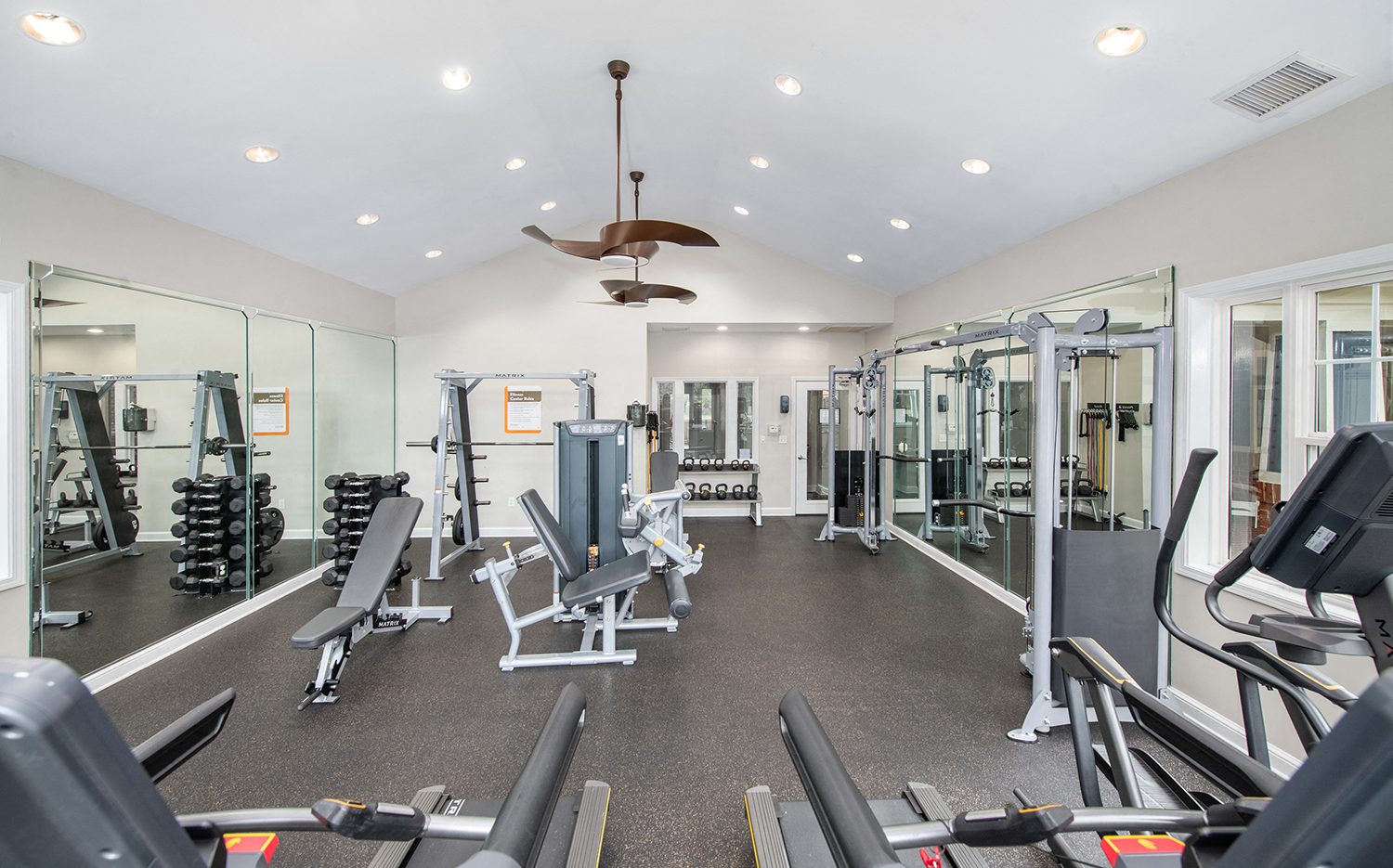 a gym with cardio equipment and weights on the floor