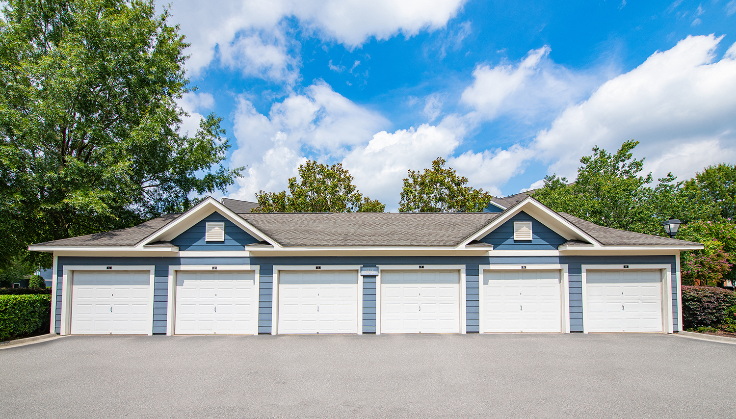 a row of white garage doors in front of a house