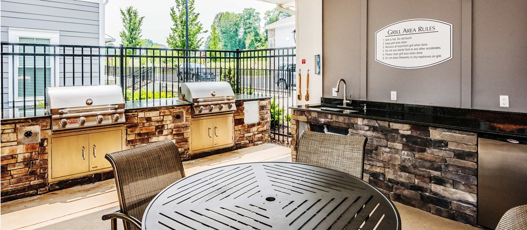 a patio with a table and barbecue grill