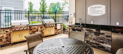 a patio with a table and barbecue grill