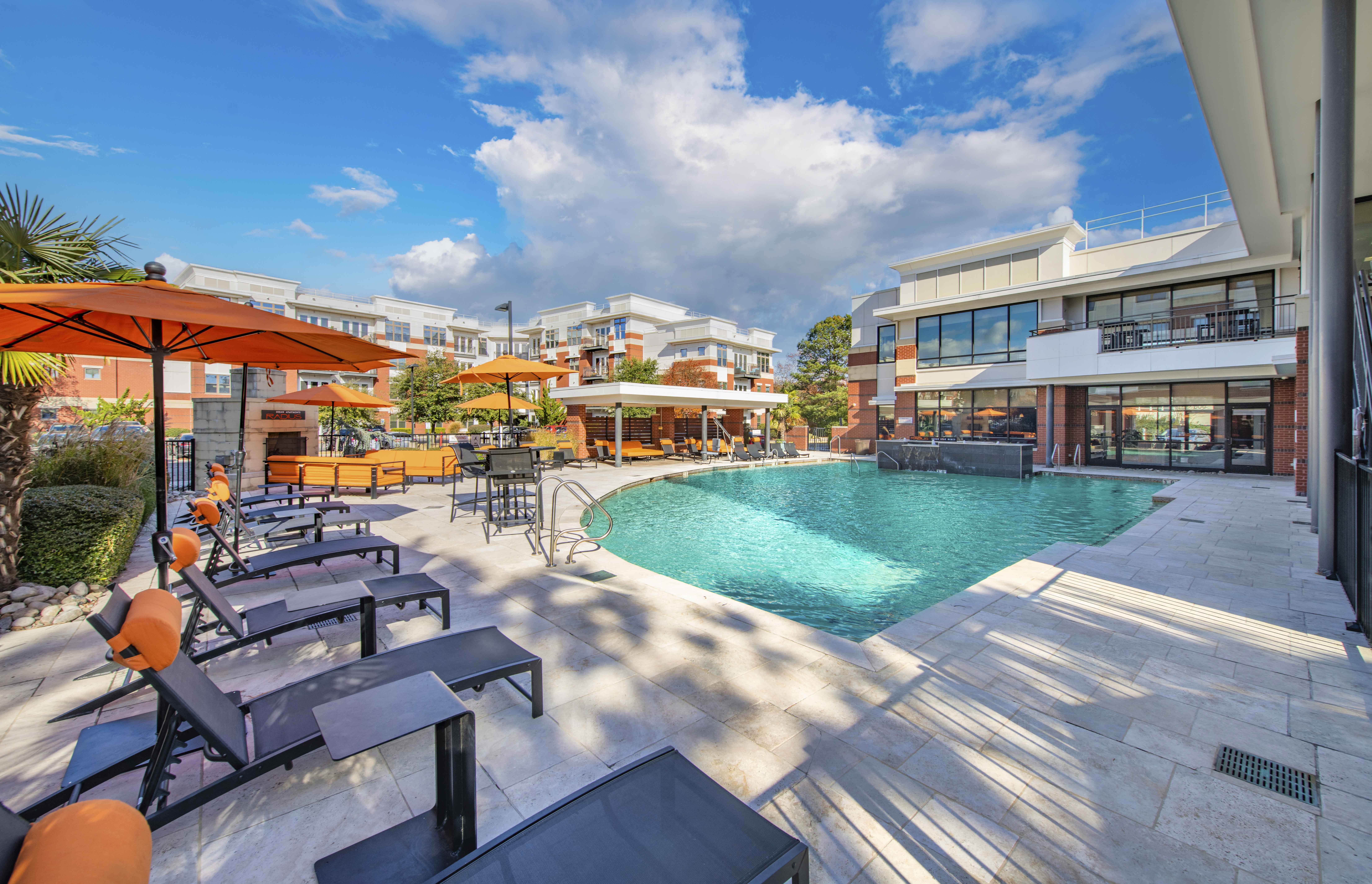 a swimming pool with patio furniture and a building in the background