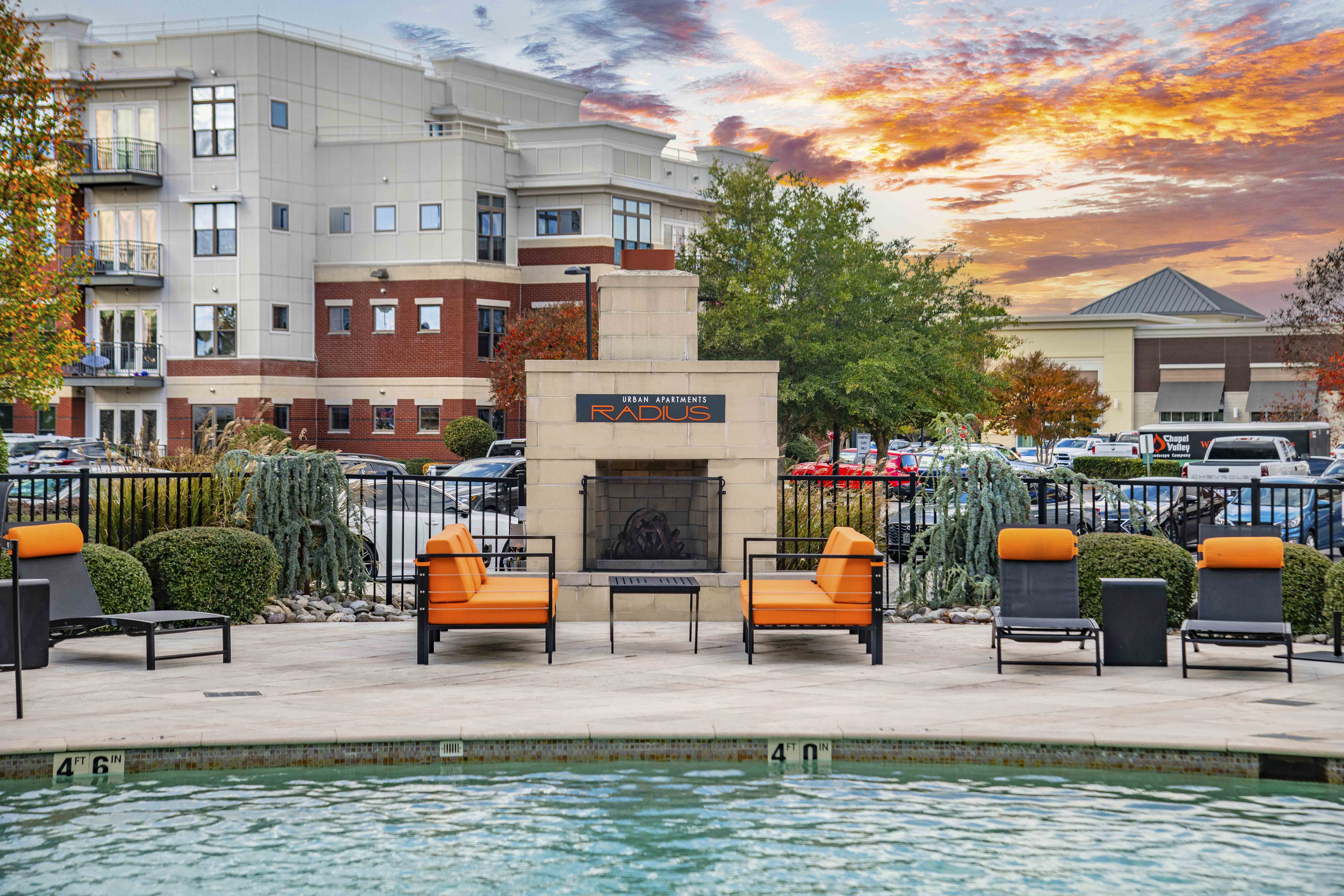 a swimming pool with chairs and a fireplace next to a hotel pool