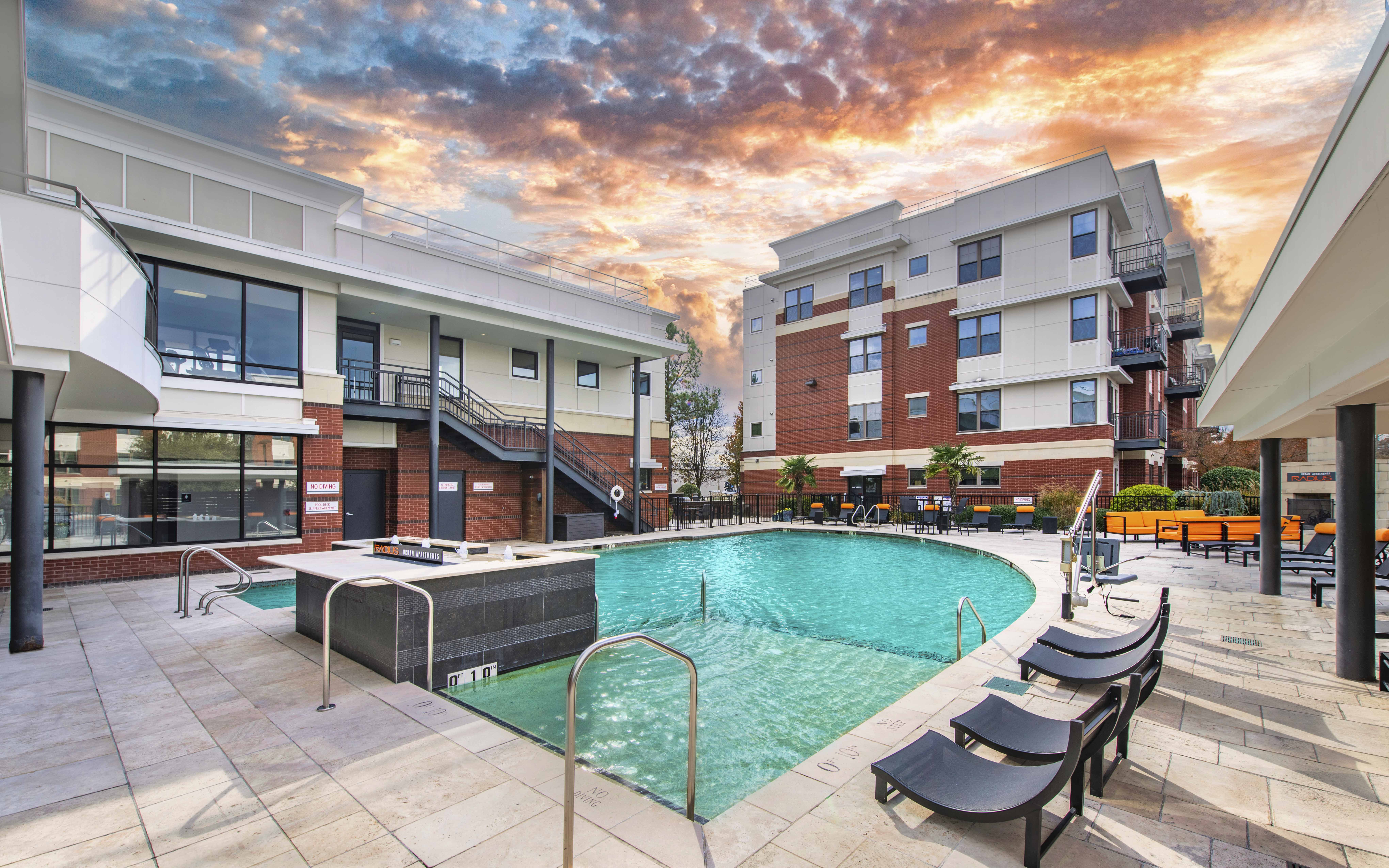 a swimming pool at a building with a sunset in the background