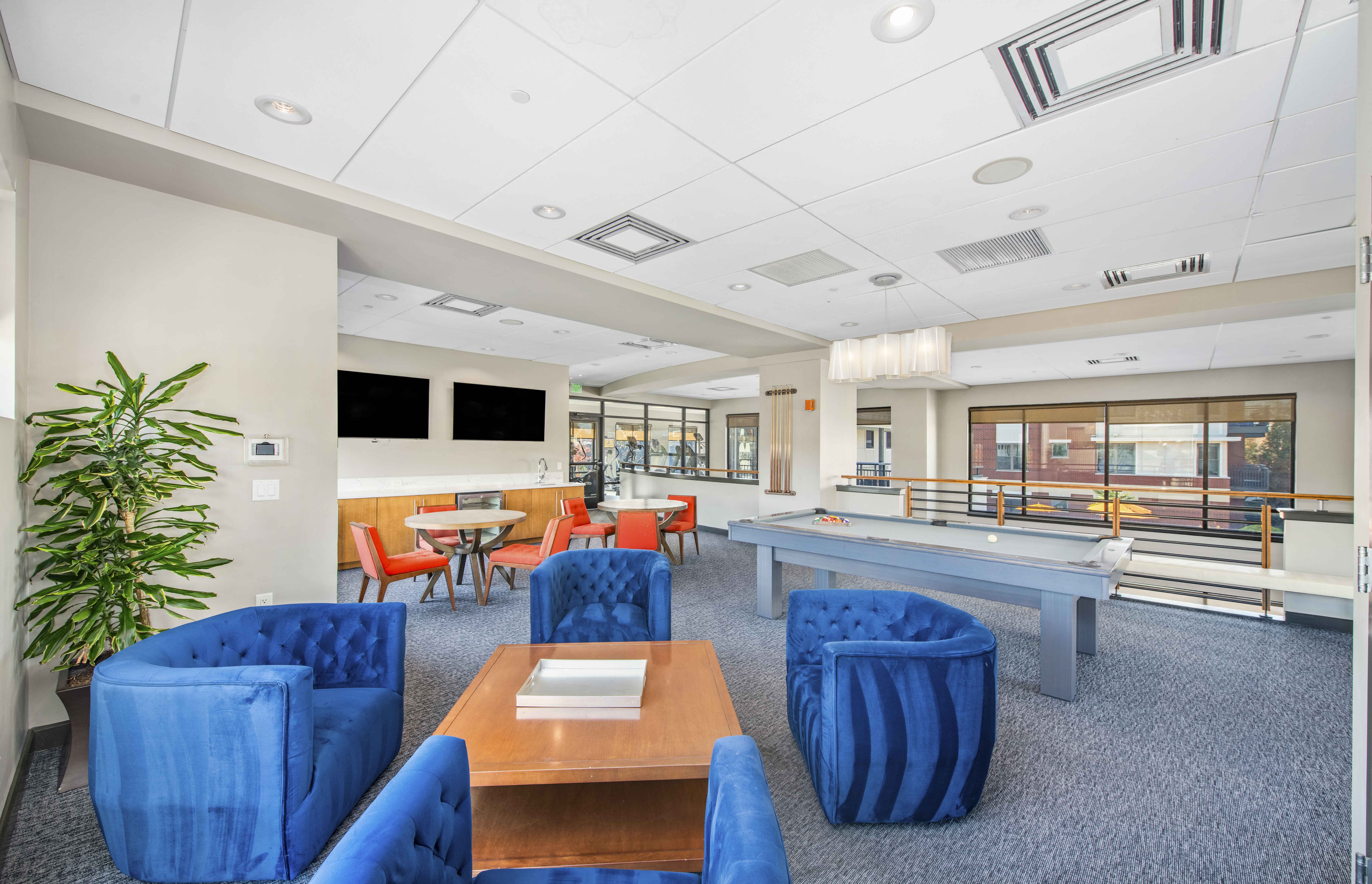 a lounge area with blue chairs and tables and a pool table