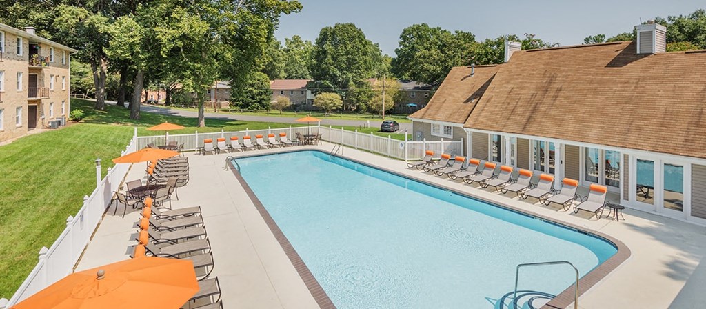 a swimming pool with orange umbrellas and chairs around it