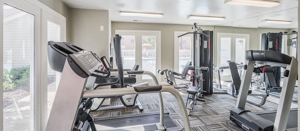 a gym with cardio equipment and windows in a building