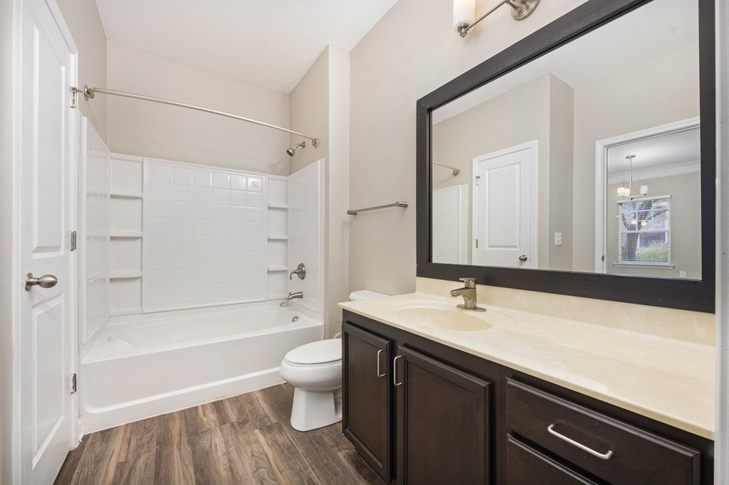 A white bathroom with a wooden floor and a white toilet.