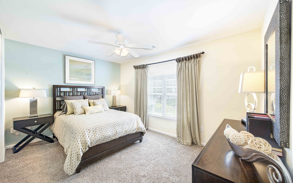 A bedroom with a bed, nightstand, and a ceiling fan.