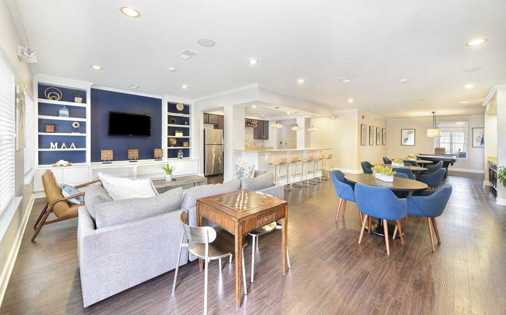 A modern living room with a grey couch, blue chairs, and a wooden table.