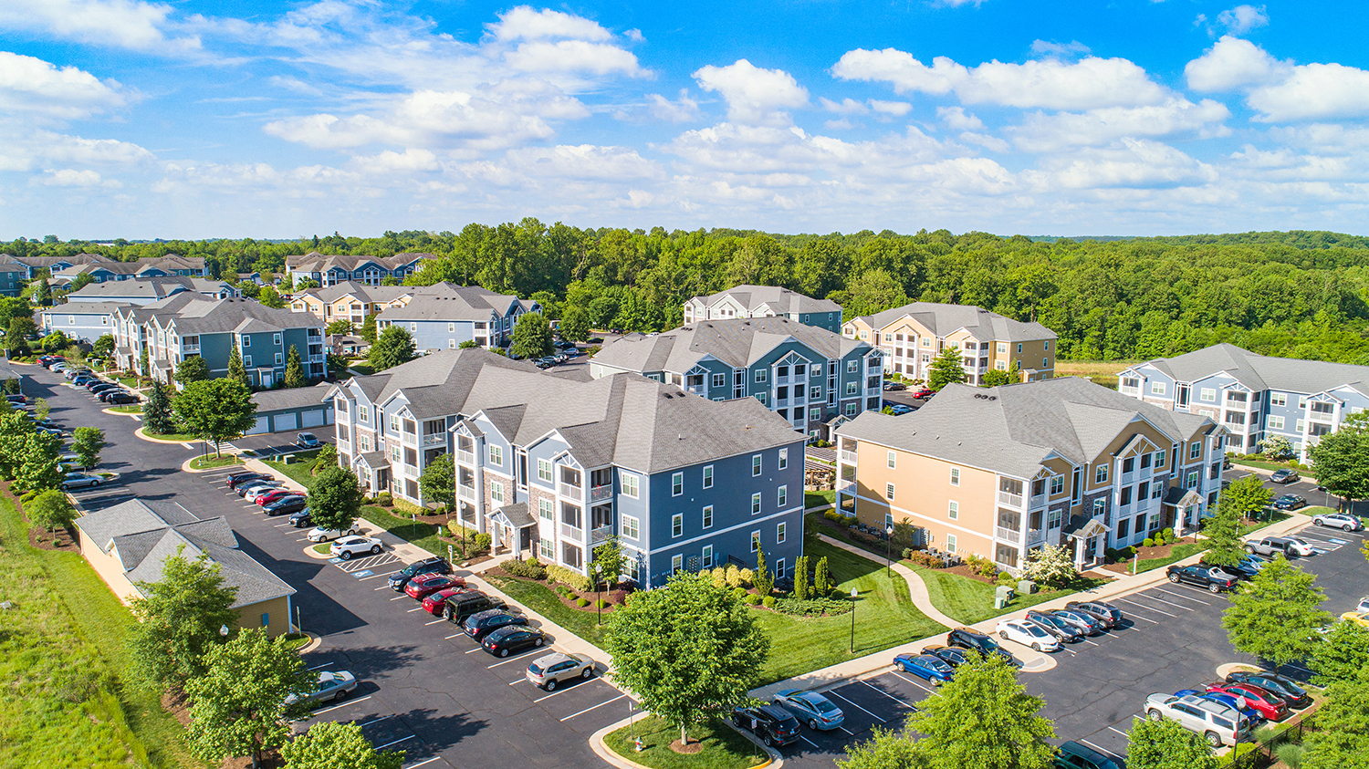 an aerial view of an apartment complex with cars parked in a parking lot