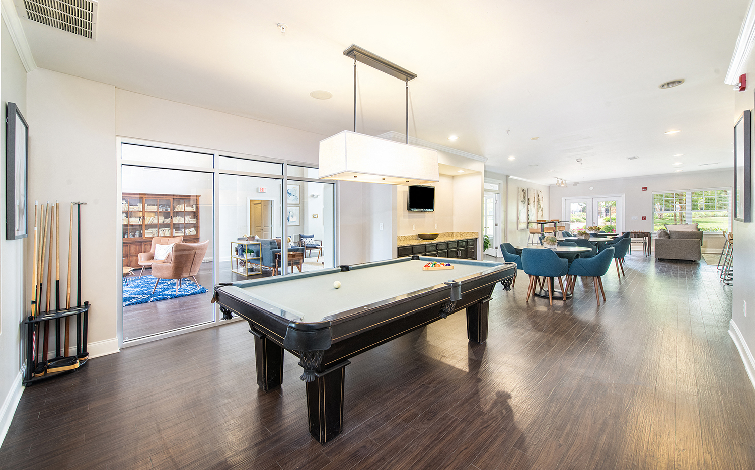 a pool table in a living room with a dining room and a kitchen