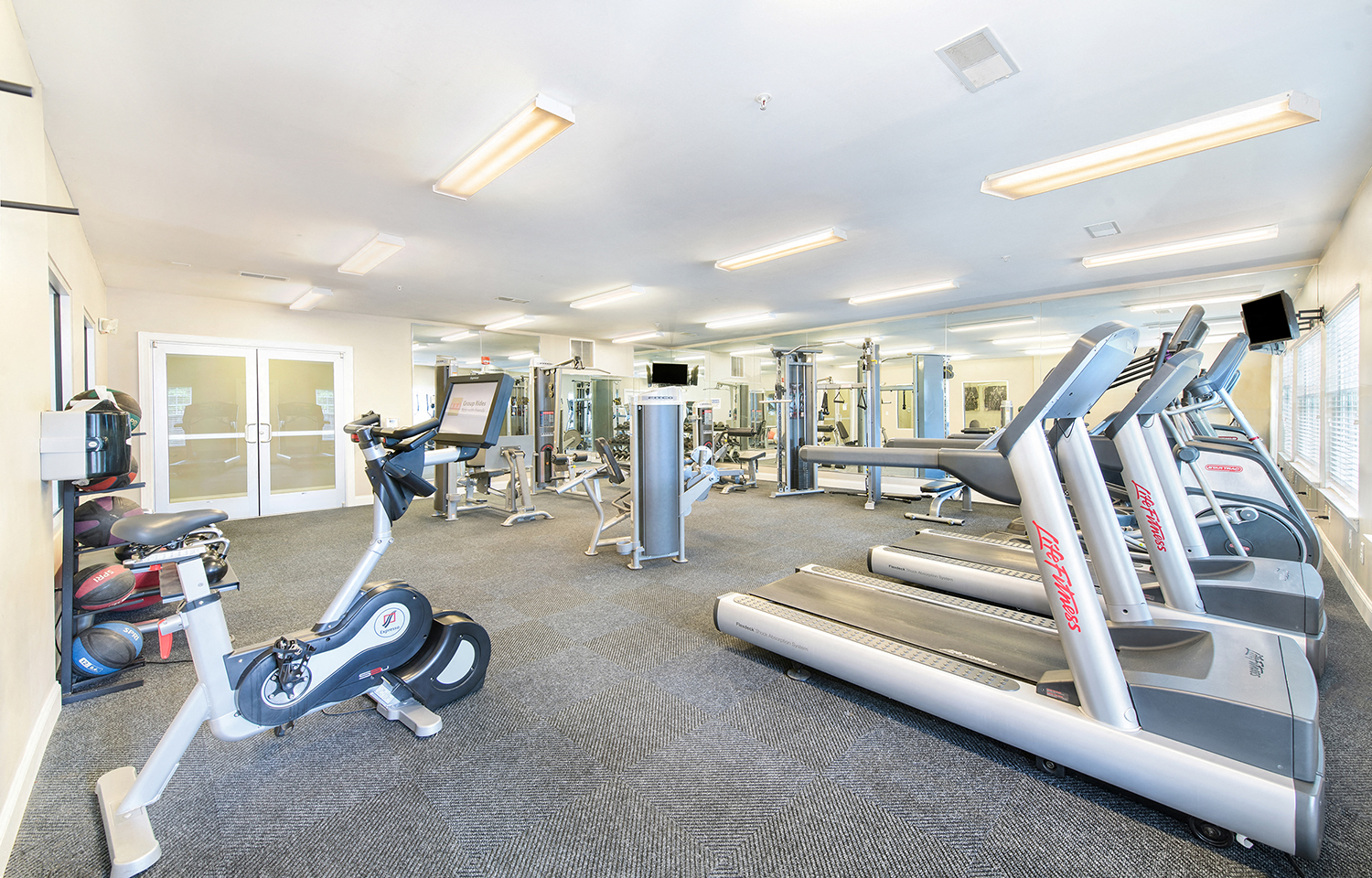 a gym with cardio equipment and weights on the floor