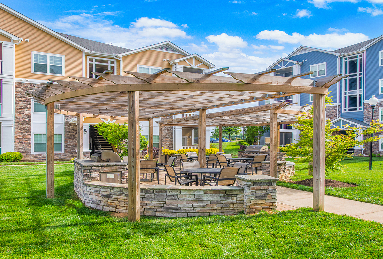 a patio with a table and chairs under a wooden pergola