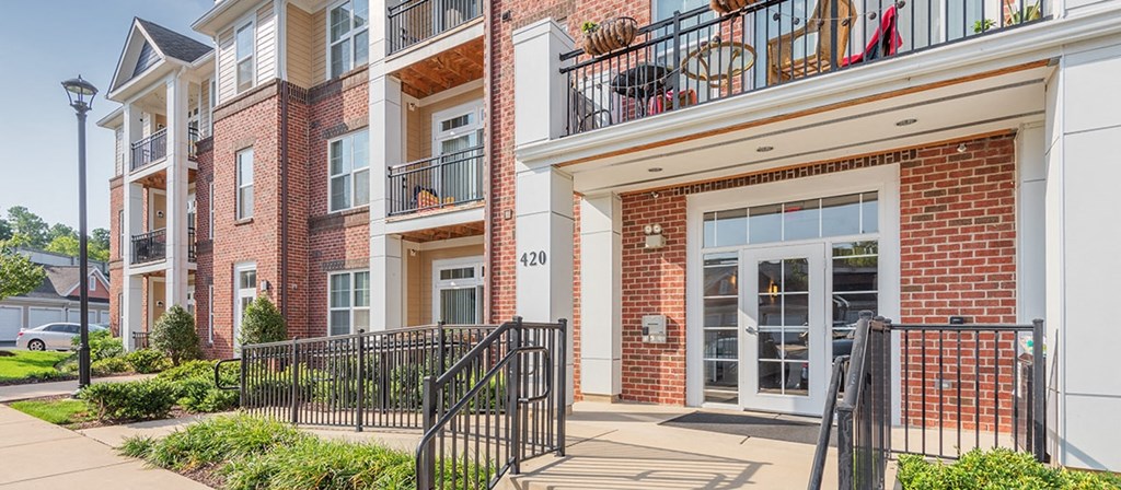 the entrance to a brick building with a staircase and a balcony