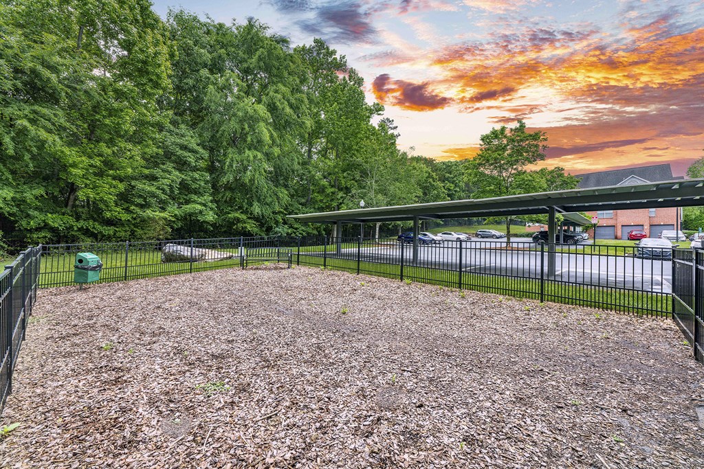 a dog park with a black fence and a parking lot