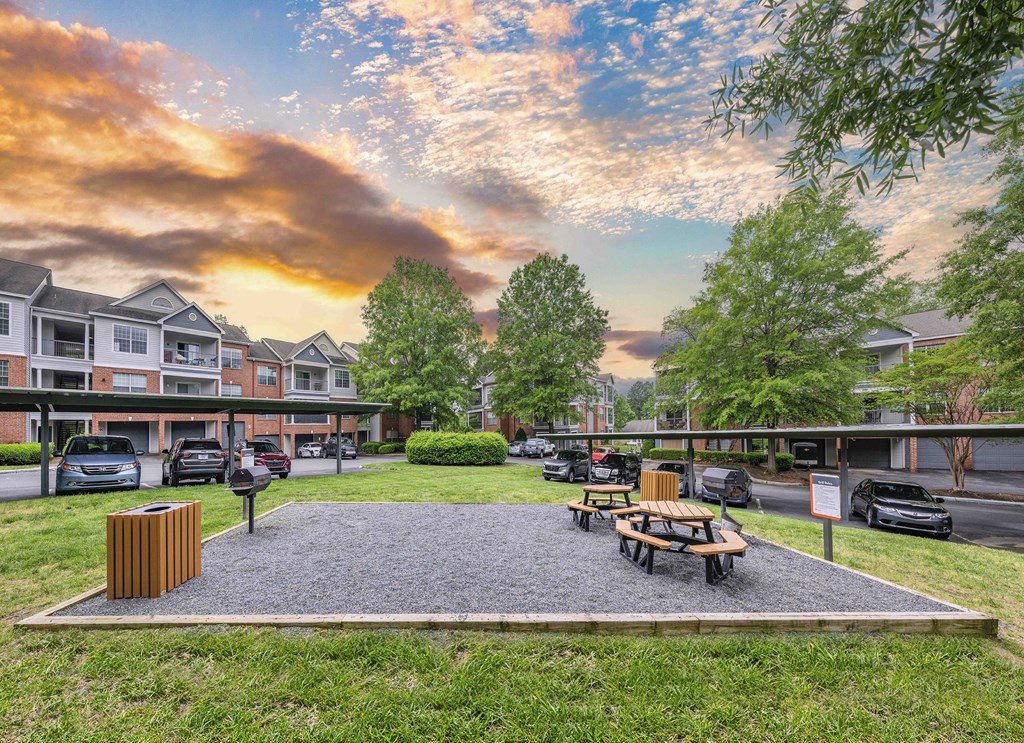 a courtyard with a picnic table and benches in front of an apartment building