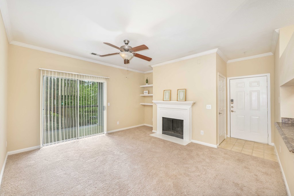 an empty living room with a fireplace and a ceiling fan