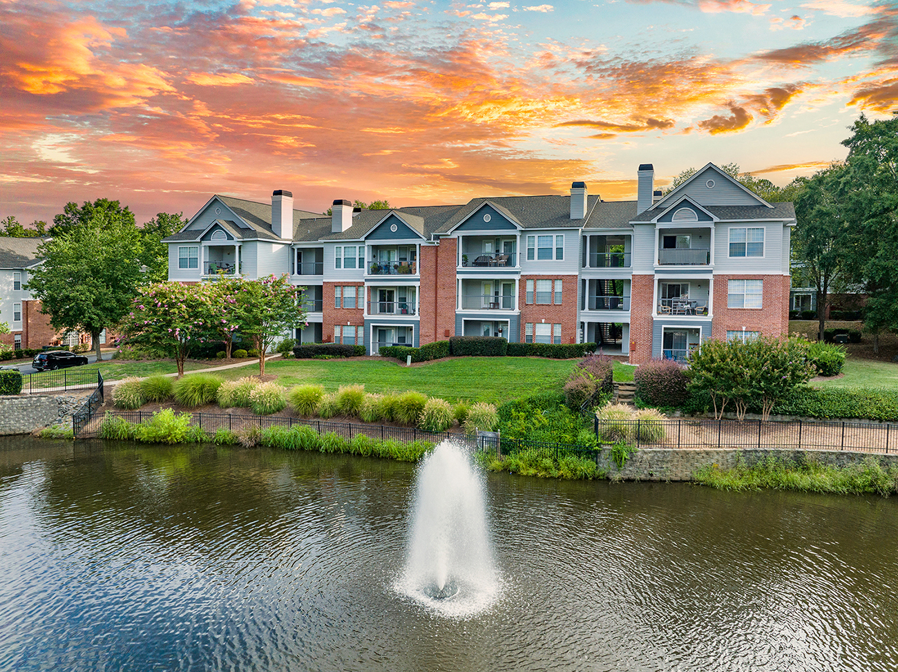 a fountain in a pond with an apartment building in the background